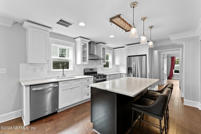 kitchen with sink, wall chimney exhaust hood, appliances with stainless steel finishes, a healthy amount of sunlight, and dark hardwood / wood-style flooring