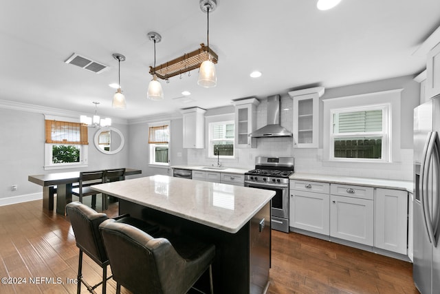 kitchen with sink, wall chimney range hood, stainless steel appliances, dark hardwood / wood-style floors, and a center island