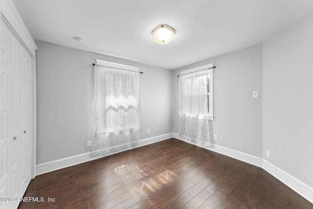 unfurnished bedroom with a closet and dark hardwood / wood-style floors