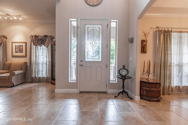 foyer with a wealth of natural light, ornamental molding, and a textured ceiling