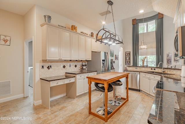 kitchen with stainless steel appliances, light hardwood / wood-style floors, sink, pendant lighting, and a textured ceiling