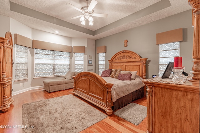 bedroom featuring multiple windows, ceiling fan, a textured ceiling, and light hardwood / wood-style flooring