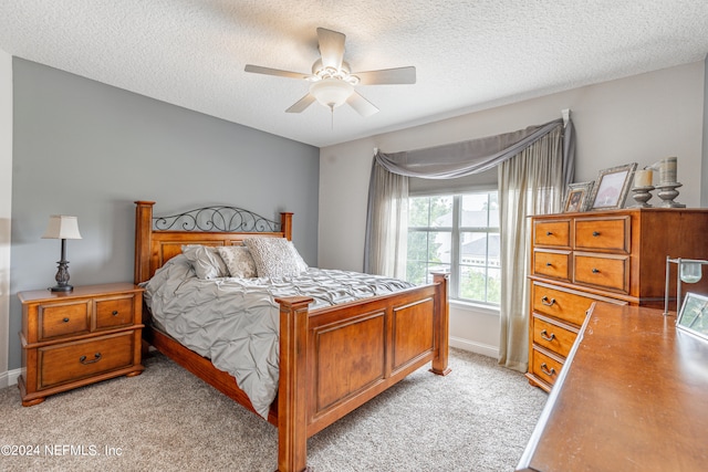 bedroom featuring ceiling fan, light carpet, and a textured ceiling