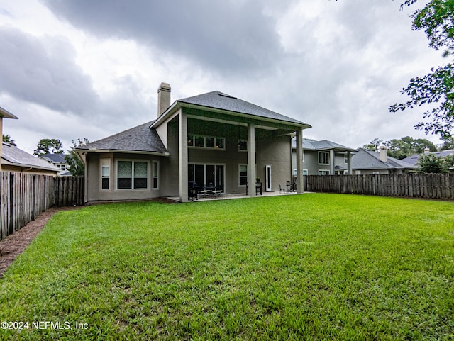 back of house with a lawn and a patio