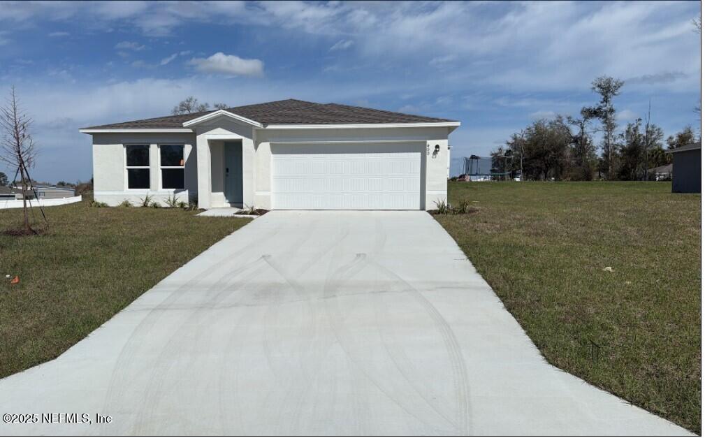 ranch-style house featuring a garage, concrete driveway, a front lawn, and stucco siding