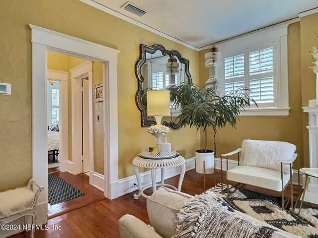 sitting room with ornamental molding and wood-type flooring