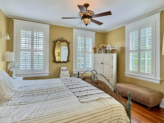 bedroom with multiple windows, ceiling fan, hardwood / wood-style flooring, and ornamental molding