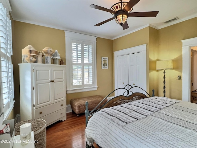 bedroom featuring dark wood-type flooring, ceiling fan, ornamental molding, and a closet