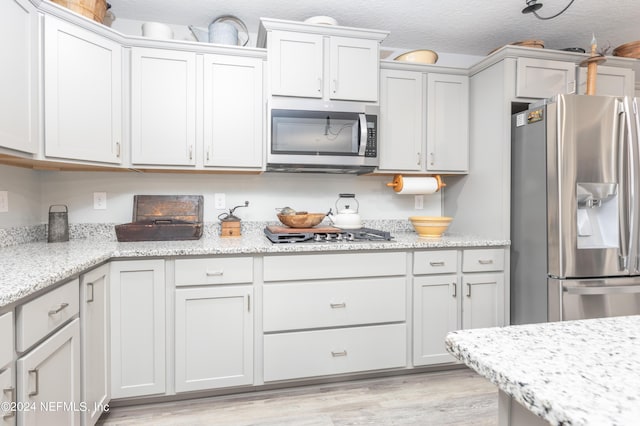 243 Bluejack Ln, Saint Augustine, FL 32095 - kitchen with light stone countertops, a textured ceiling, appliances with stainless steel finishes, and light wood finished floors