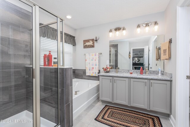 bathroom featuring vanity, separate shower and tub, a textured ceiling, and tile patterned floors