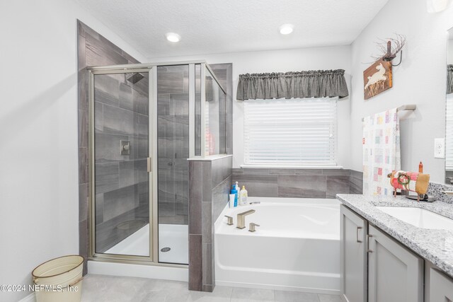 bathroom featuring a textured ceiling, shower with separate bathtub, and vanity