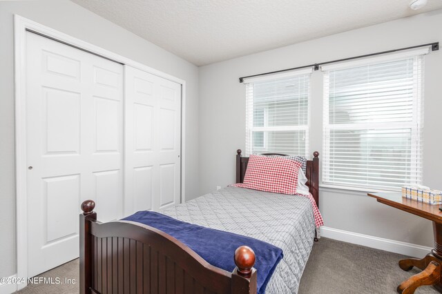 bedroom with carpet floors, a textured ceiling, and a closet