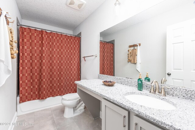 full bathroom featuring vanity, a textured ceiling, shower / tub combo with curtain, toilet, and tile patterned floors