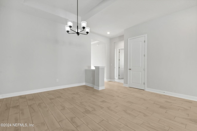 unfurnished room with a chandelier and light wood-type flooring