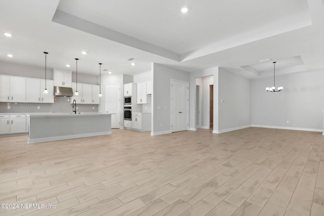 85212 Sandy Ridge Loop Unit 0023, Yulee, FL 32097 - unfurnished living room featuring a tray ceiling, recessed lighting, a sink, light wood finished floors, and baseboards