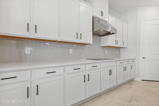 kitchen with white cabinets, black electric stovetop, backsplash, and range hood