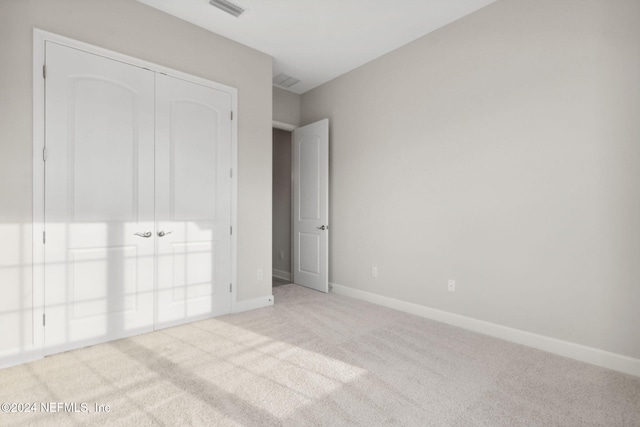 unfurnished bedroom featuring light carpet and a closet