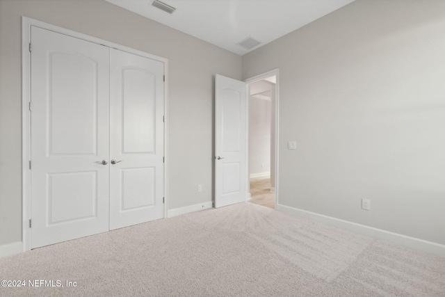 unfurnished bedroom featuring a closet and light colored carpet