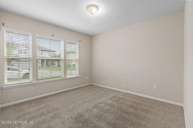 carpeted empty room featuring a textured ceiling