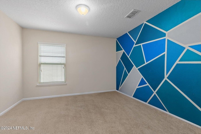 carpeted empty room featuring a textured ceiling