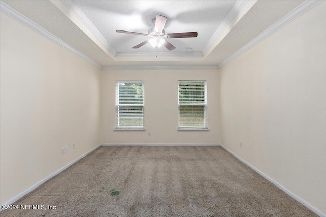 spare room with light carpet, crown molding, a textured ceiling, ceiling fan, and a tray ceiling