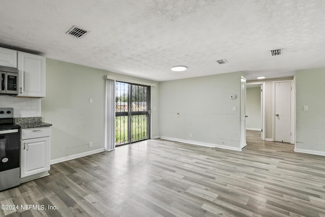 5246 Devron Dr, Jacksonville, FL 32209 - kitchen featuring stainless steel appliances, a textured ceiling, light wood-type flooring, baseboards, and white cabinetry
