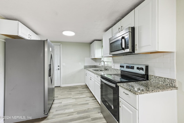5246 Devron Dr, Jacksonville, FL 32209 - kitchen with stainless steel appliances, a sink, light wood-style flooring, and white cabinets