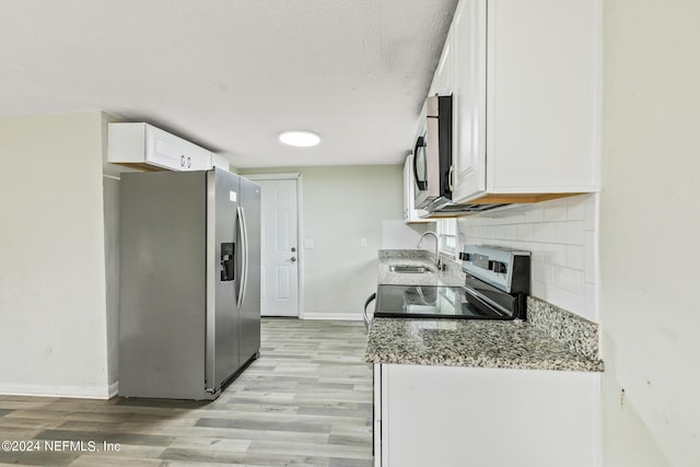 5246 Devron Dr, Jacksonville, FL 32209 - kitchen with appliances with stainless steel finishes, a sink, baseboards, light wood-style flooring, and white cabinets