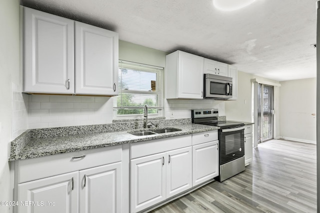 5246 Devron Dr, Jacksonville, FL 32209 - kitchen with appliances with stainless steel finishes, a sink, a textured ceiling, light wood-type flooring, and tasteful backsplash