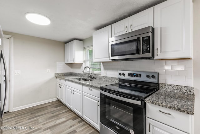 5246 Devron Dr, Jacksonville, FL 32209 - kitchen featuring appliances with stainless steel finishes, a sink, decorative backsplash, white cabinetry, and light wood-type flooring