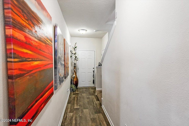 hall featuring a textured ceiling and dark wood-type flooring