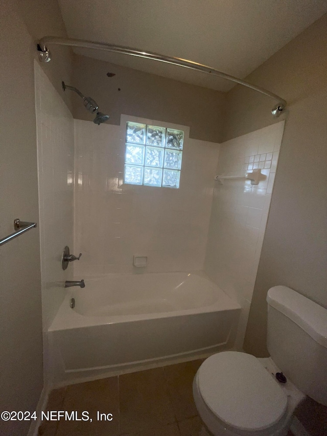 bathroom featuring tiled shower / bath, toilet, and tile patterned flooring