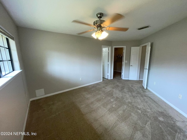 unfurnished bedroom featuring a closet, ceiling fan, carpet, and a spacious closet