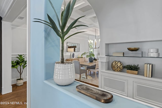 room details with a notable chandelier, beamed ceiling, hardwood / wood-style flooring, and ornamental molding