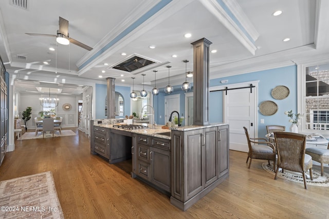 kitchen featuring pendant lighting, ornamental molding, a barn door, ceiling fan with notable chandelier, and hardwood / wood-style floors