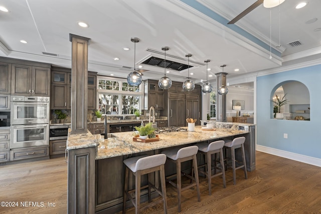 kitchen featuring pendant lighting, ornamental molding, a large island, dark hardwood / wood-style floors, and stainless steel double oven