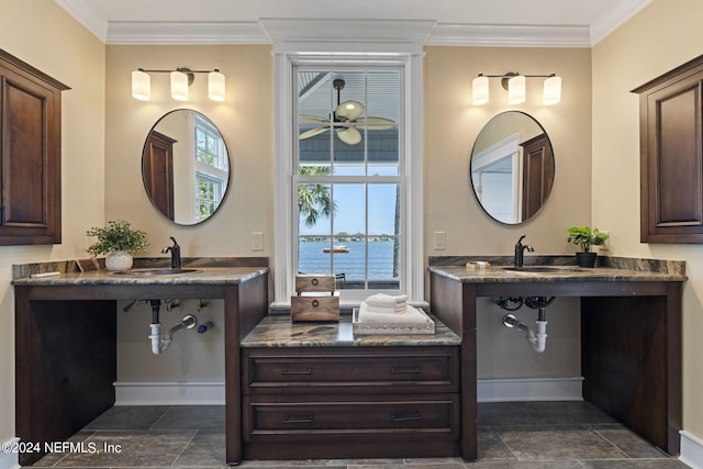 bathroom featuring crown molding, a water view, and dual sinks