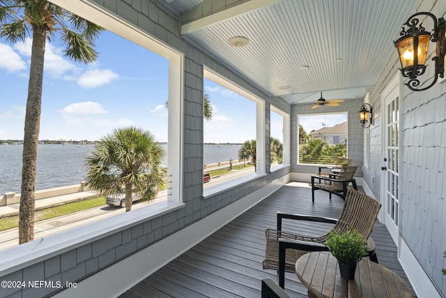 deck with a water view and ceiling fan