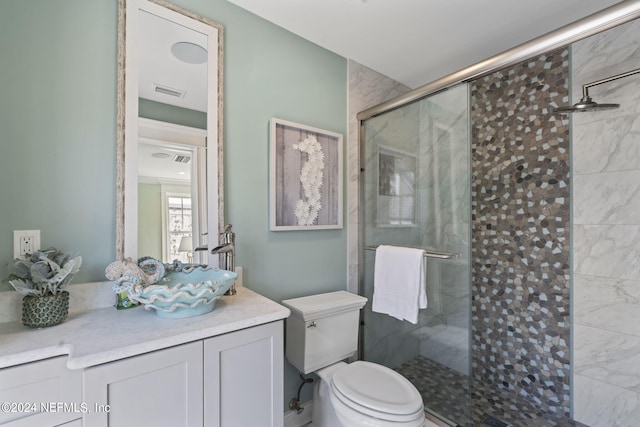 bathroom featuring a shower with door, toilet, and vanity