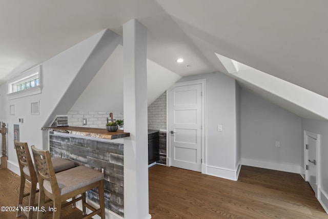 interior space with lofted ceiling, dark hardwood / wood-style floors, and bar