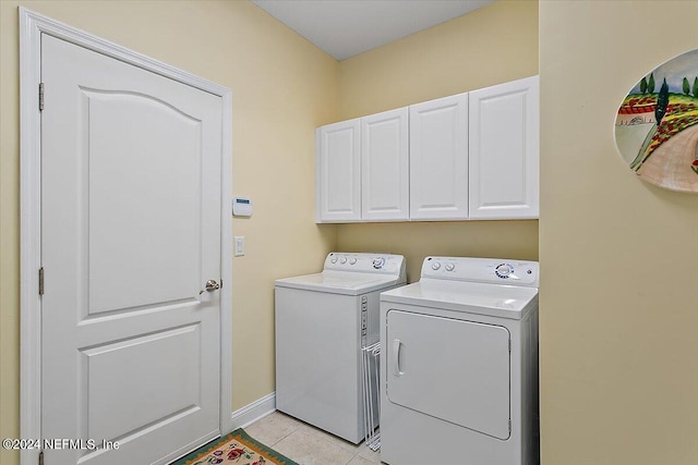 laundry area featuring light tile patterned floors, cabinets, and washer and clothes dryer