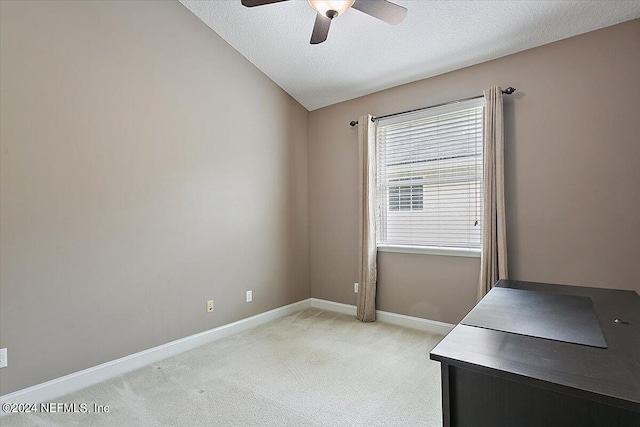 home office with ceiling fan, vaulted ceiling, light carpet, and a textured ceiling