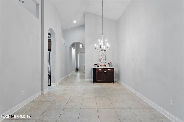 hall featuring a notable chandelier, light tile patterned floors, and high vaulted ceiling