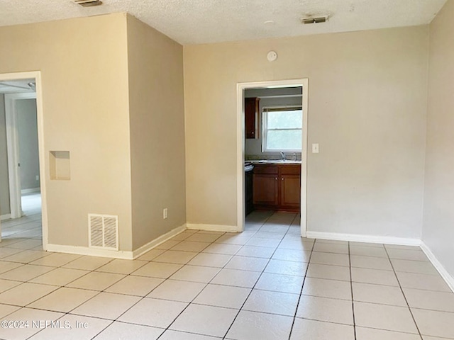 tiled spare room featuring a textured ceiling and sink