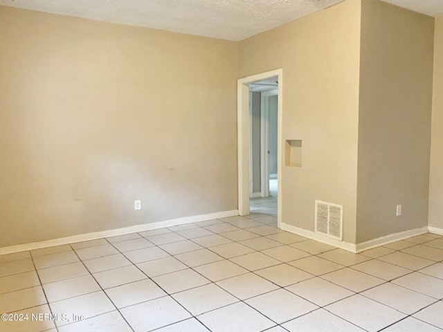 tiled empty room with a textured ceiling