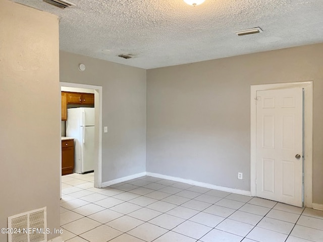 tiled spare room featuring a textured ceiling