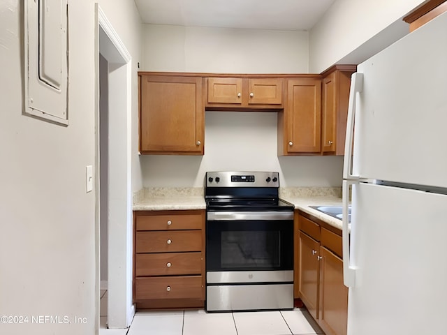 kitchen with stainless steel range with electric stovetop, white refrigerator, electric panel, and light tile patterned flooring