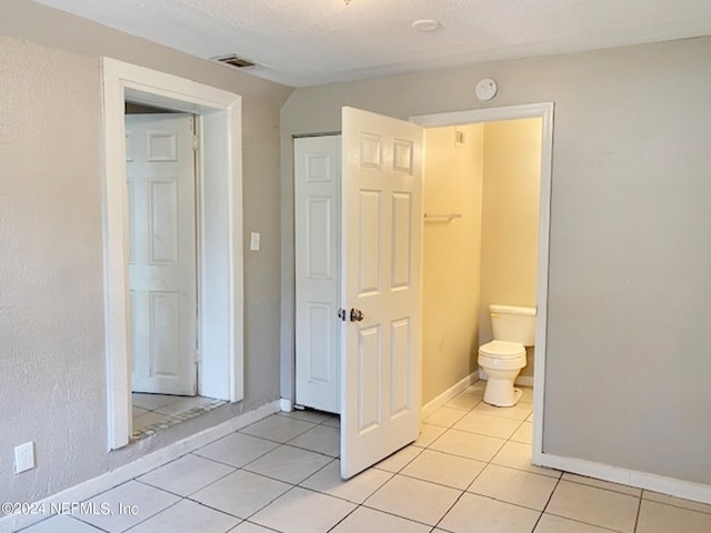 bathroom with tile patterned flooring, a textured ceiling, and toilet