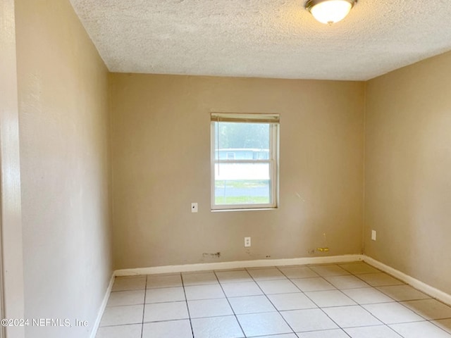 tiled empty room with a textured ceiling