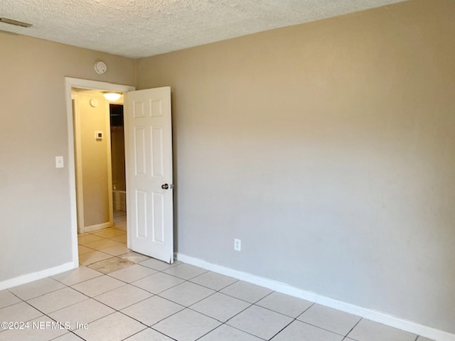 tiled spare room with a textured ceiling